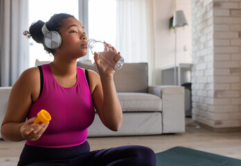 Woman resting after home workout, drinking water. New Year's resolutions, healthy lifestyle, losing...