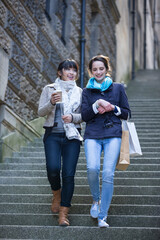 Two happy women shopping together, having fun and laughing