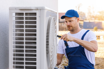 technician working on air conditioning or heat pump outdoor unit. HVAC service, maintenance and...