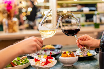 Two people clinking wine glasses over a table filled with gourmet dishes, celebrating a moment in an elegant setting