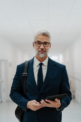 Portrait of pharmaceutical sales representative in medical building, waiting for doctor, presenting new pharmaceutical product. Smiling drug rep standing in hall holding tablet. - 750486335