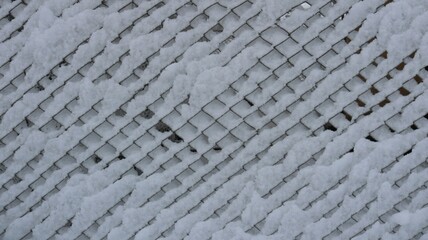 Snow sticking on a wire mesh fence, a fragment of fencing from a grate covered with a layer of wet fresh snow, a white texture graphic resource of winter with a geometric pattern