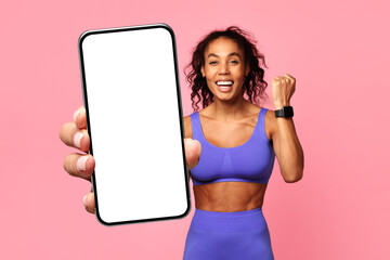 Athletic African woman showcases cell phone screen gesturing yes, studio