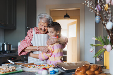 Grandmother with granddaughter preparing traditional easter meals, baking cakes and sweets. Passing...