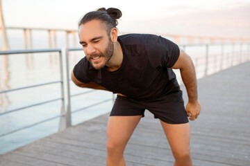 Sporty man in pain holding his side after outdoor workout