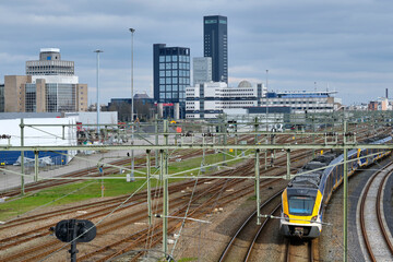 View of the Leeuwarden train station and the Leeuwarden skyline with a network of railroad tracks and overhead lines under a dark cloudy sky. Leeuwarden is the capitol of Friesland The Netherlands