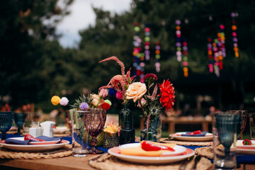 Red flower arrangements in vases, colorful decor, autumn flowers. On the festive table in the wedding banquet area, compositions of flowers and greenery, candles are placed.