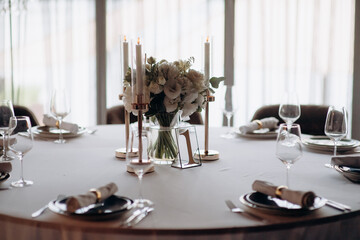 Floral arrangements of white flowers in transparent glass vases. On the festive table in the wedding banquet area, compositions of flowers and greenery, candles are placed.