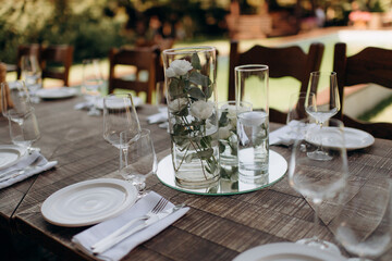 Floral arrangements of white flowers in transparent glass vases. On the festive table in the wedding banquet area, compositions of flowers and greenery, candles are placed.