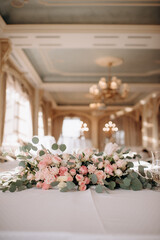 A large flower arrangement of white and pink flowers for the newlyweds' table, decoration of the presidium. On the festive table in the wedding banquet area, compositions of flowers and greenery, cand