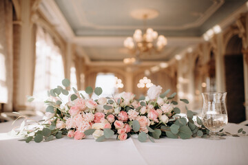 A large flower arrangement of white and pink flowers for the newlyweds' table, decoration of the presidium. On the festive table in the wedding banquet area, compositions of flowers and greenery, cand