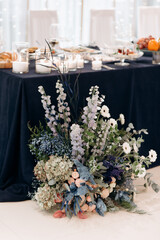 A large flower arrangement of white and pink flowers for the newlyweds' table, decoration of the presidium. On the festive table in the wedding banquet area, compositions of flowers and greenery, cand