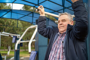 Mature man with content expression working out on exercise equipment in outdoor park setting.