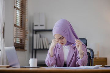 Young asian islamic women stressed from work at office desk.