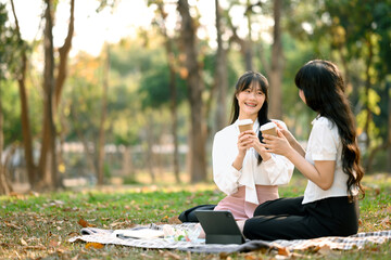 Attractive Asian business people talking and drinking coffee in the park after work