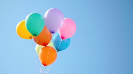 A bunch of colorful balloons against a clear blue sky