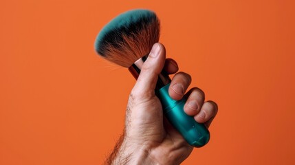 Close-up of a hand holding a soft bristle brush on a vibrant orange background, representing tools in modern male grooming - obrazy, fototapety, plakaty