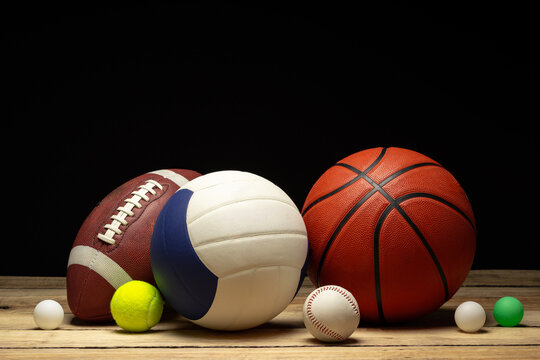 Set of various sport balls on wooden floor on black background - Powered by Adobe