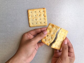 Hand holding cracker on plain background