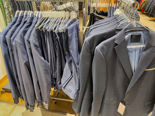 New men's luxury suit clothes on hangers in a  boutique clothing store