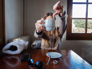 Mujer joven en la cafetería pidiendo mas cafe. Bebida caliente un dia frío.