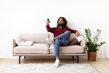 Relaxed young indian man watching TV at home