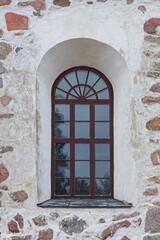 Fototapeta na wymiar Brown painted wood frames on a window with arch on a stone building.