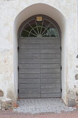 Old wooden door with window on top on a stone building.