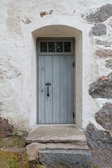 Old wooden door with window on top on a stone building.