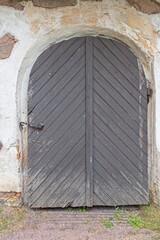Fototapeta na wymiar Old wooden door with arch on a stone building.