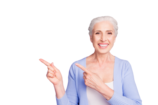 Beautiful nice cheerful smiling gray-haired old lady wearing casual, showing pointing way with two fingers. Copy space. Isolated over pastel violet purple background