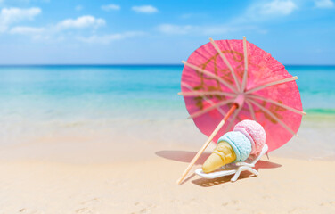 Ice cream cone with pink paper umbrella on tropical beach, summer outdoor day light