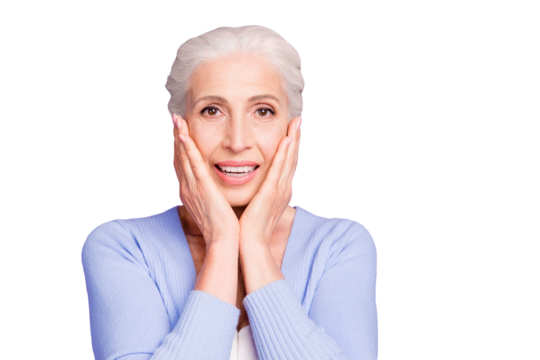 Portrait of grey haired old nice beautiful amazed shocked smiling woman with palms on cheeks. Isolated over violet purple background