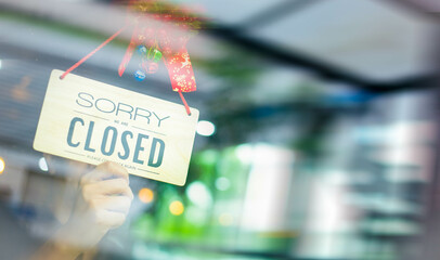 The waitress man turning Closed sign board on glass door in modern cafe coffee shop, cafe...