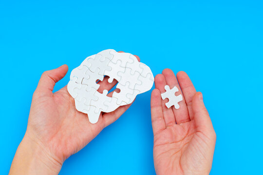 Holding Brain-Shaped White Jigsaw Puzzle with Missing Element