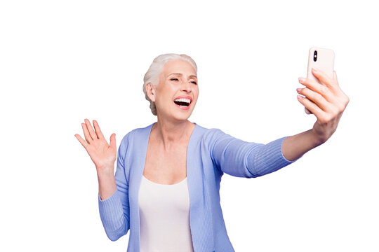 Grey haired old happy excited funny funky woman wearing casual, taking self picture, waving to cam, opened mouth. Isolated over violet purple background