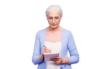 Gray haired old serious business woman wearing glasses, writing plans strategy in paper note book with pen. Isolated over violet purple background