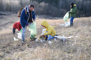 Little girl among eco activists picking up litter in nature, environmental pollution, eco activism and plogging concept.