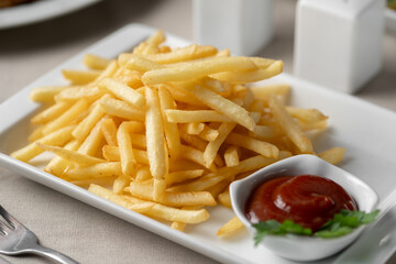 Plate of french fries potatoes served with ketchup on white plate. Unhealthy food