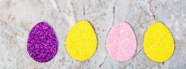 four glitter easter eggs in a row on marble background