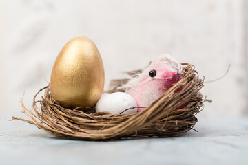 Easter decoration bird and gold egg in bird nest