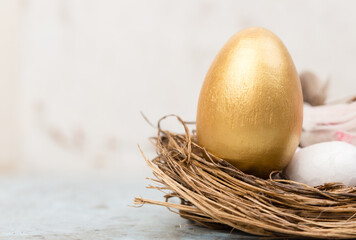 Golden Easter egg decoration in a bird nest with copy space