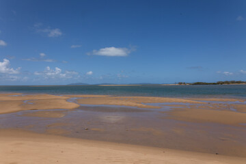 Fototapeta na wymiar A landscape of a tropical beach at low tide with an offshore spit and exposed sand banks and blue sky with clouds at Taylor's Beach near Cardwell in Queensland, Australia