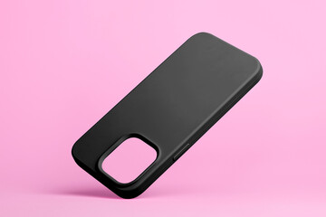 smartphone in black soft silicone case falls down back view, phone case mockup isolated on grey...