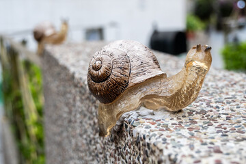 A close-up image of a snail statue crawling along a wall, showcasing the beauty of slow movement in...