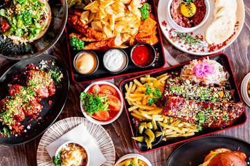 An enticing spread of dishes on a rustic wooden table: golden fries, meatballs, fresh salad, and...