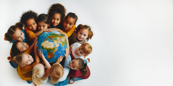 The earth surrounded by children on a white background. The concept of Earth day.
