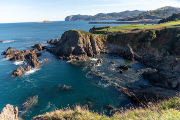 Panoramic view of the Basque coastal landscape of cliffs, calm sea and green vegetation on a sunny day with clear sky