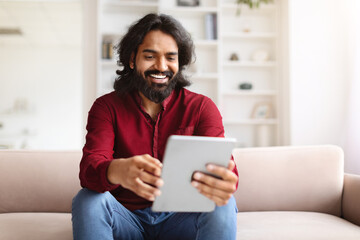 Smiling eastern man watching video content on digital tablet