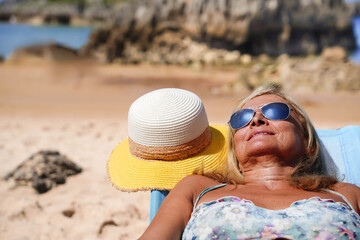 mature woman in sunglasses sunbathing on the beach in summer